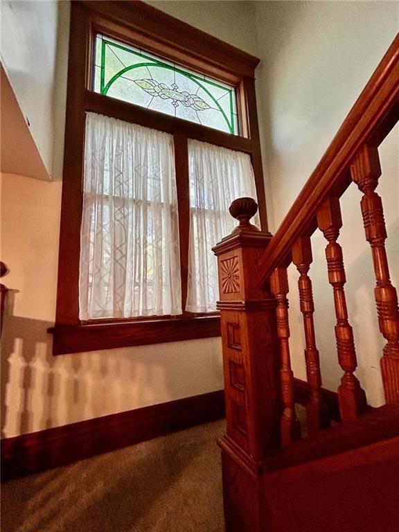 carpeted foyer entrance with stairs and baseboards