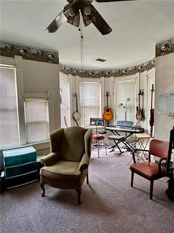 sitting room with ceiling fan and carpet