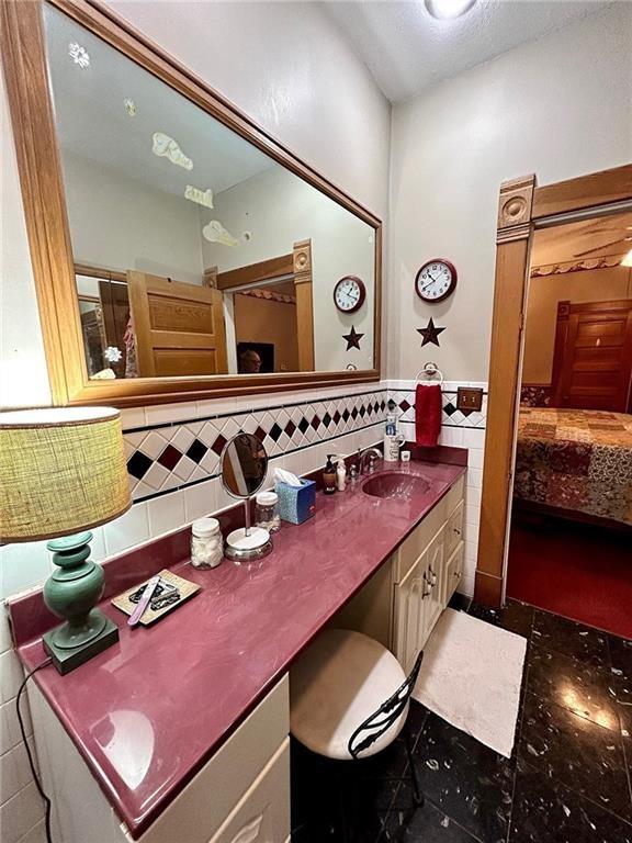 bathroom with tile walls, vanity, and ensuite bath