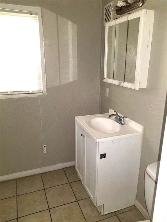 2109 E 58th St, Kansas City, MO 64130 - bathroom with vanity, toilet, tile patterned floors, and baseboards
