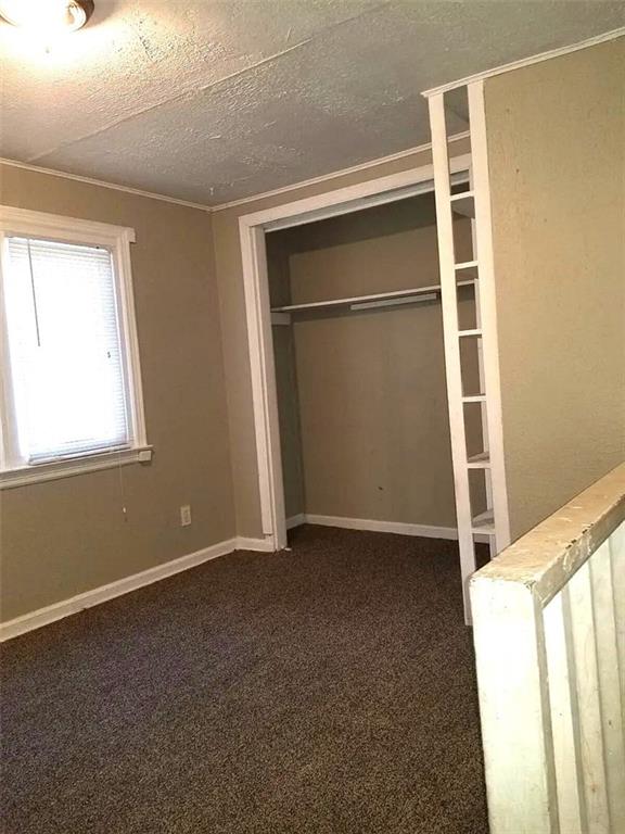 2109 E 58th St, Kansas City, MO 64130 - unfurnished bedroom featuring dark carpet, a closet, and a textured ceiling