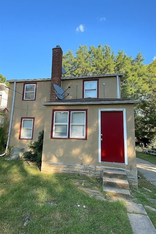 5610 Euclid Ave, Kansas City, MO 64130 - rear view of property featuring entry steps, stucco siding, a chimney, and a yard