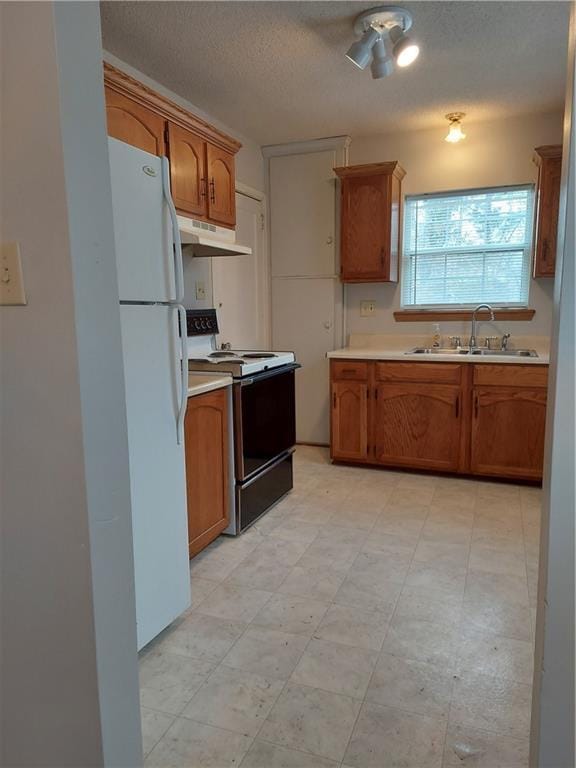 1610 S Northern Blvd, Independence, MO 64052 - kitchen featuring under cabinet range hood, electric stove, a sink, freestanding refrigerator, and brown cabinetry
