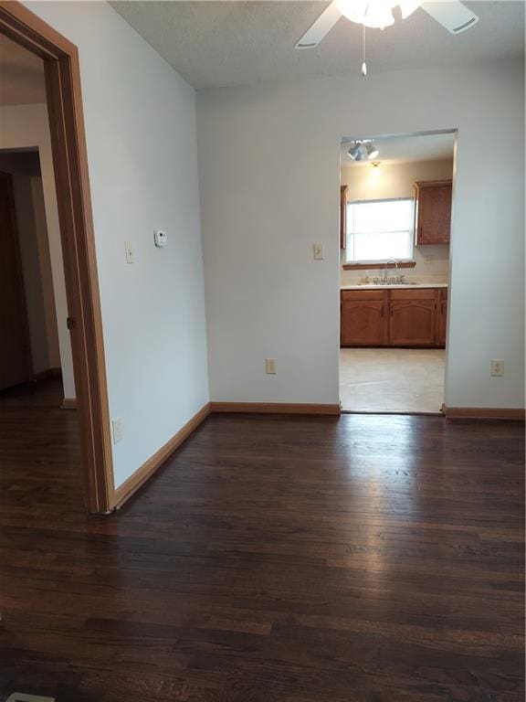 1610 S Northern Blvd, Independence, MO 64052 - spare room with baseboards, a ceiling fan, dark wood-type flooring, and a sink