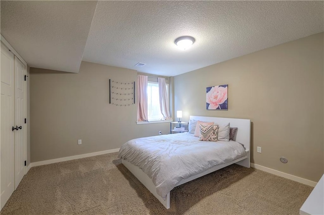 bedroom with a textured ceiling, visible vents, baseboards, and carpet