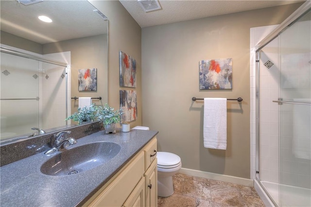 bathroom with visible vents, vanity, toilet, baseboards, and a shower stall