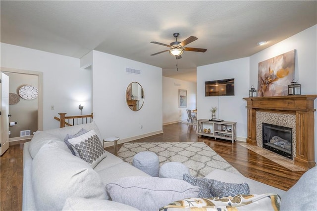 living area with a ceiling fan, visible vents, wood finished floors, and a fireplace
