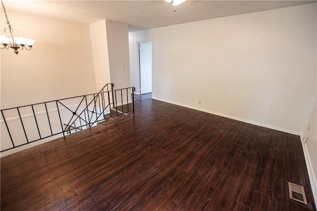 spare room with a chandelier, hardwood / wood-style flooring, and baseboards