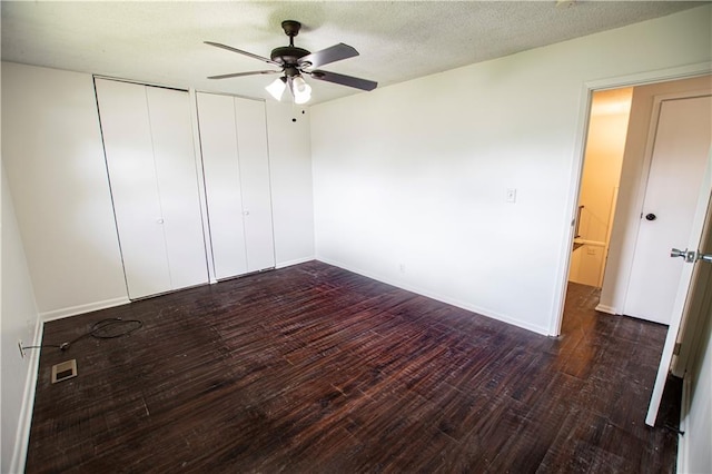unfurnished bedroom with wood finished floors, multiple closets, a ceiling fan, and baseboards