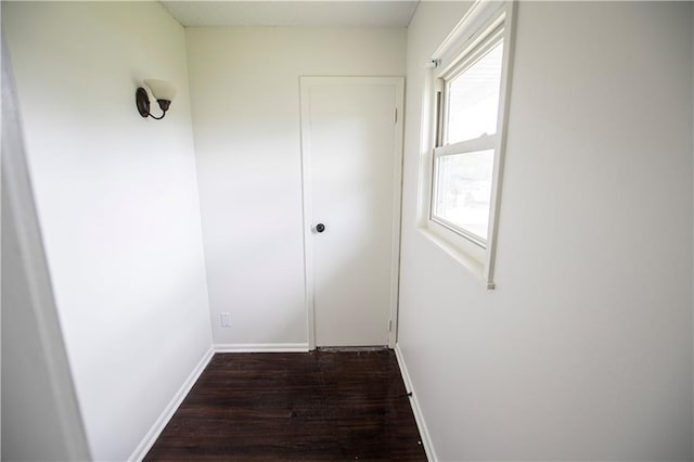 corridor featuring dark wood-style floors and baseboards