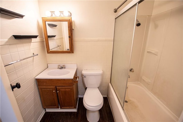 bathroom with tile walls, vanity, toilet, shower / bathtub combination, and a wainscoted wall