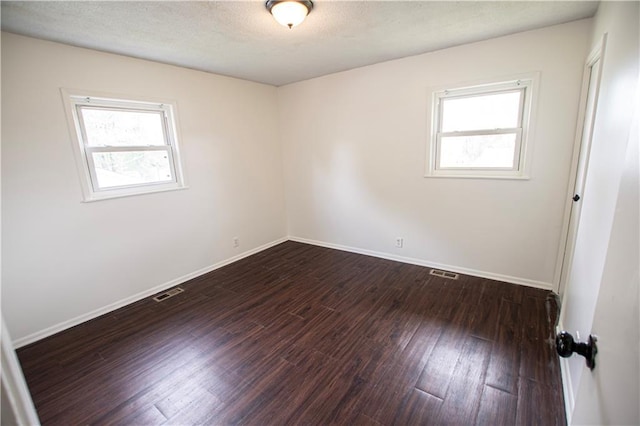 spare room with wood finished floors, healthy amount of natural light, and baseboards