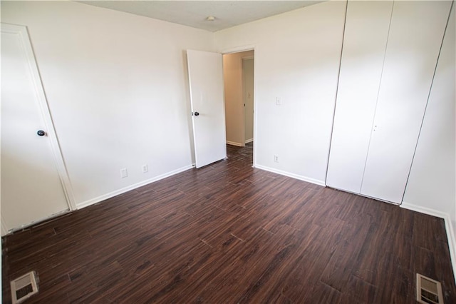 unfurnished bedroom featuring dark wood-type flooring, baseboards, and a closet