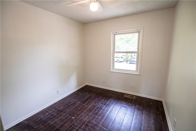 spare room with ceiling fan, a textured ceiling, dark wood-type flooring, and baseboards