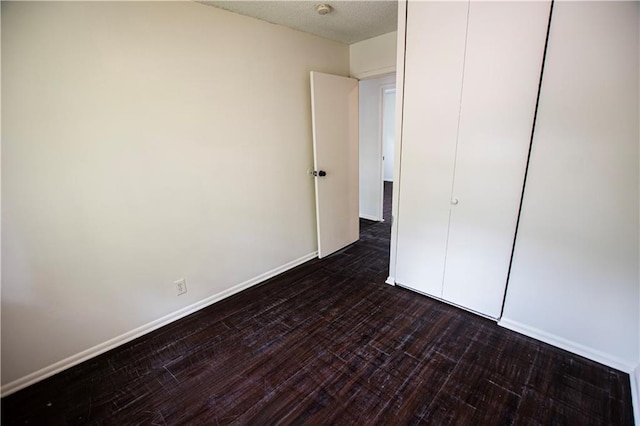 unfurnished bedroom with dark wood-style flooring and baseboards