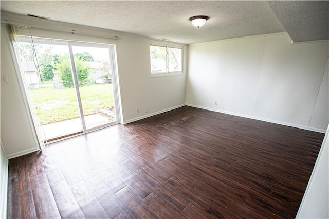 unfurnished room with a textured ceiling, dark wood finished floors, and baseboards