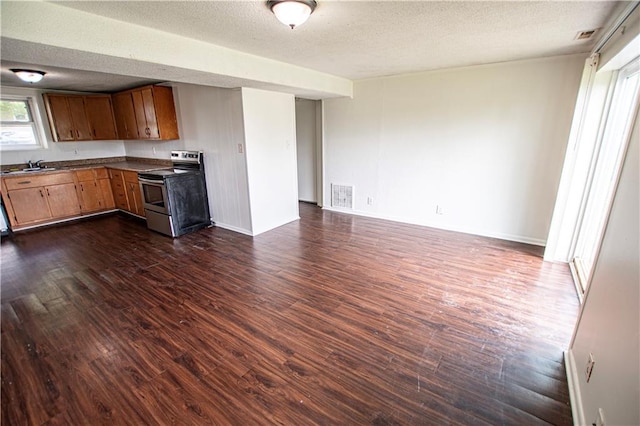 kitchen with stainless steel range with electric stovetop, dark wood-style flooring, a sink, dark countertops, and open floor plan