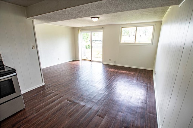 unfurnished room with dark wood-style flooring, wood walls, baseboards, and a textured ceiling