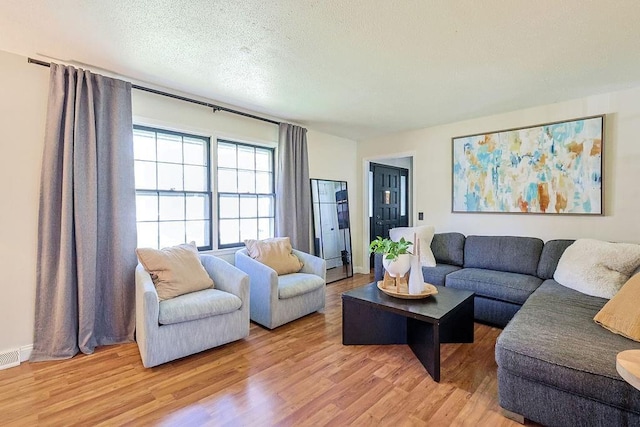 living room featuring light wood-type flooring and a textured ceiling