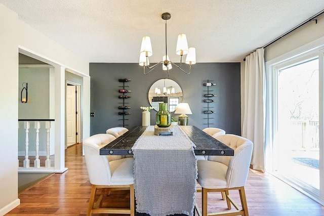 dining area featuring a chandelier, a textured ceiling, and light wood-style floors