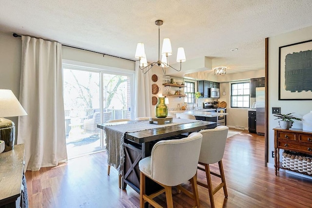 dining area featuring a chandelier, wood finished floors, and a textured ceiling