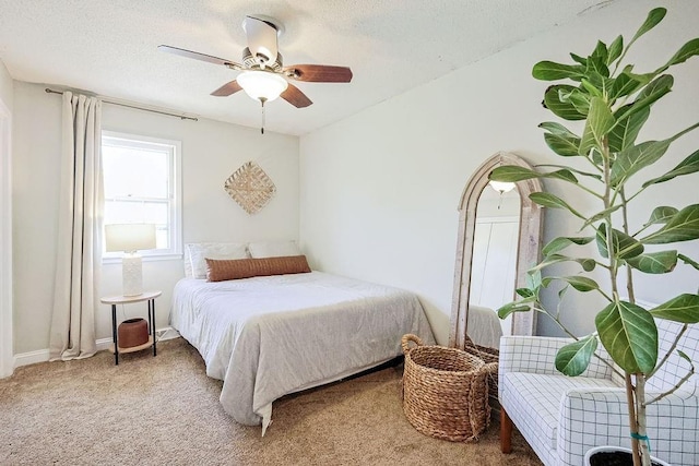 carpeted bedroom featuring a ceiling fan and a textured ceiling
