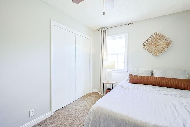 carpeted bedroom with a closet, baseboards, ceiling fan, and a textured ceiling
