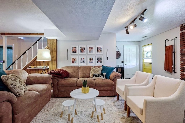 carpeted living room with rail lighting, a textured ceiling, and stairs