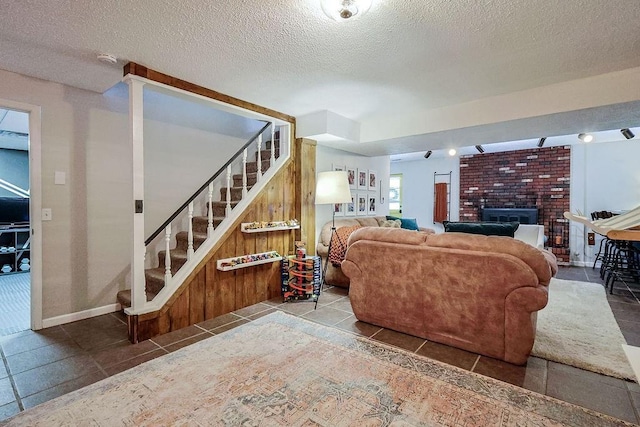 living area with stairway, a textured ceiling, a fireplace, tile patterned flooring, and baseboards