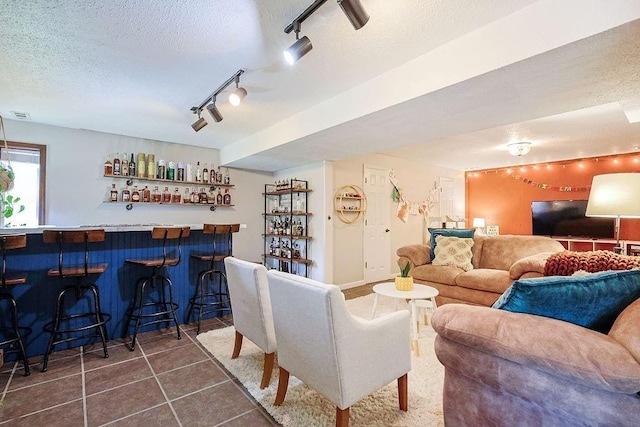 living room with track lighting, a dry bar, dark tile patterned flooring, and a textured ceiling