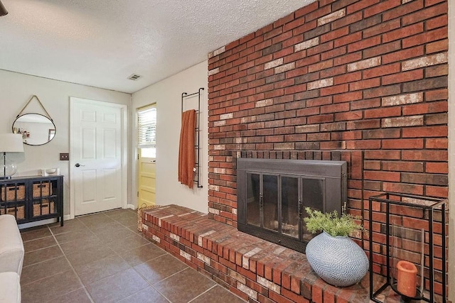 living area with a textured ceiling, dark tile patterned flooring, and a fireplace