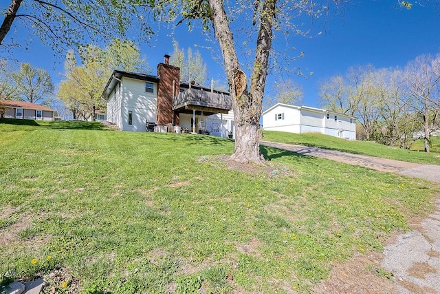 view of front of house featuring a chimney, a wooden deck, and a front lawn
