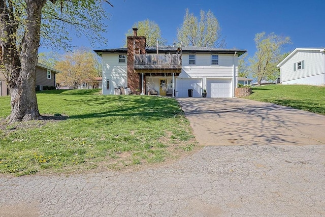 rear view of house featuring a chimney, a garage, driveway, and a lawn