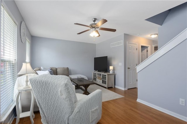 living room with baseboards, a ceiling fan, wood finished floors, and visible vents