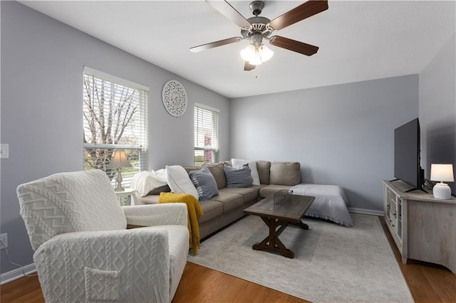 living room featuring ceiling fan, baseboards, and wood finished floors