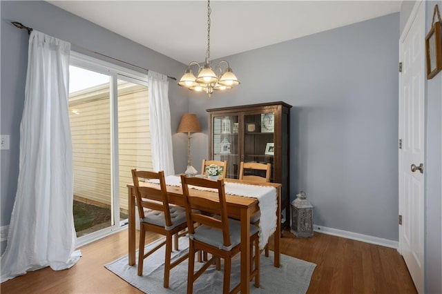 dining space with wood finished floors, baseboards, and an inviting chandelier
