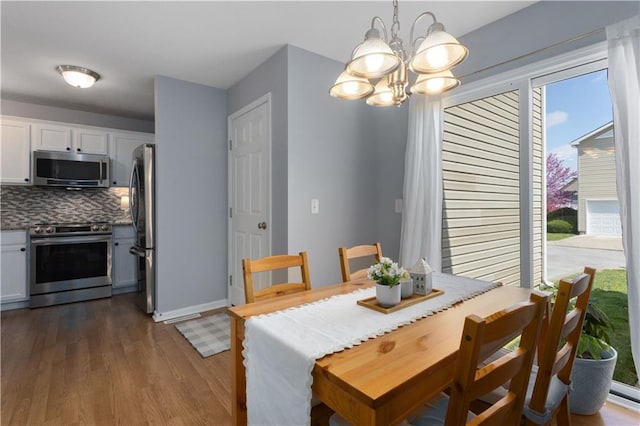 dining space featuring a chandelier, baseboards, and dark wood-style flooring