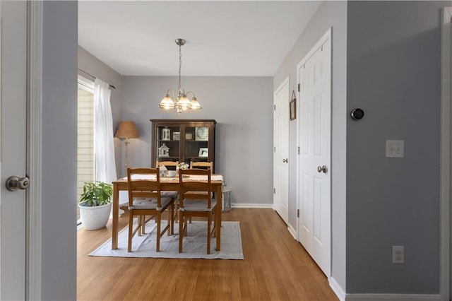 dining space with baseboards, wood finished floors, and a chandelier