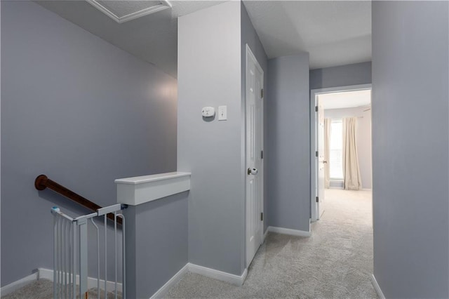 hall featuring carpet, baseboards, and an upstairs landing