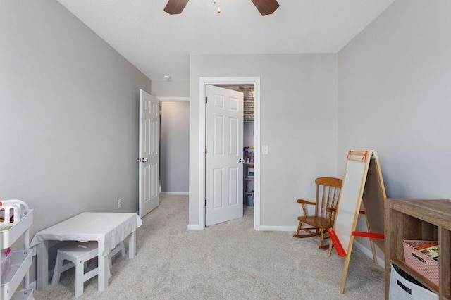 living area with a ceiling fan, baseboards, and light carpet