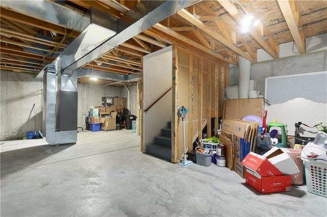 unfinished basement featuring stairs and heating unit