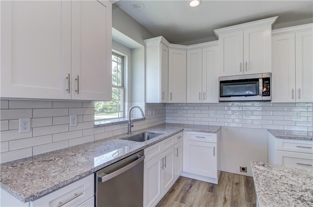 1828 N 92nd Ter, Kansas City, KS 66112 - kitchen with light stone counters, stainless steel appliances, a sink, light wood-type flooring, and white cabinetry