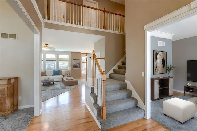 stairs with wood finished floors, visible vents, and ceiling fan