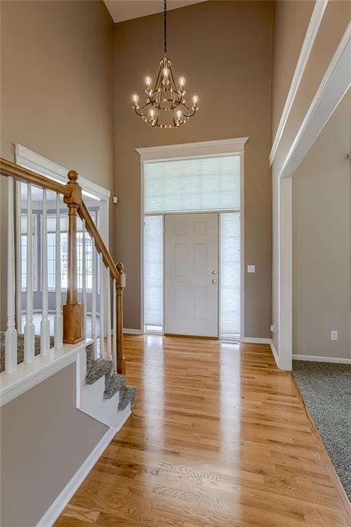 entrance foyer featuring a wealth of natural light, a high ceiling, stairs, and a notable chandelier