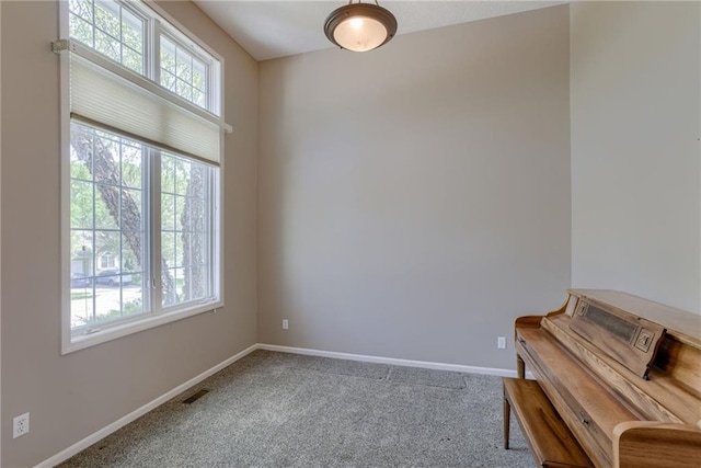 unfurnished room with carpet floors, visible vents, and baseboards