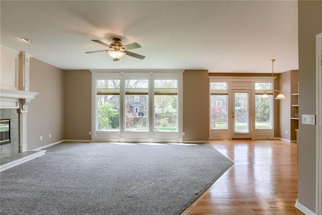 unfurnished living room featuring a fireplace, plenty of natural light, a textured ceiling, and ceiling fan