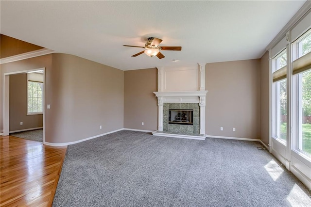 unfurnished living room featuring baseboards, a ceiling fan, and a tile fireplace