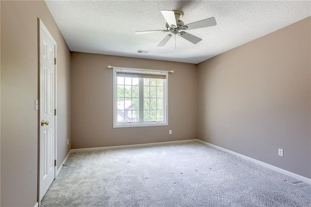 carpeted empty room featuring ceiling fan, baseboards, a textured ceiling, and visible vents