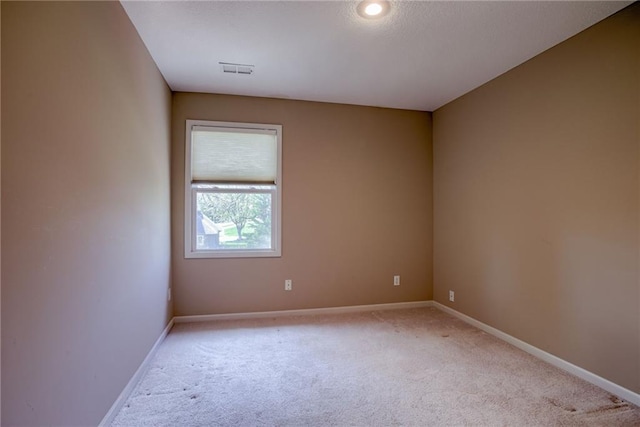 unfurnished room with visible vents, light carpet, and baseboards