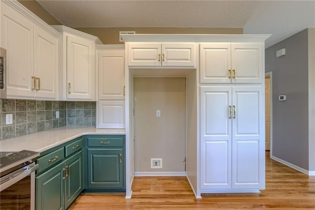 kitchen with decorative backsplash, green cabinetry, white cabinetry, and light wood-style flooring